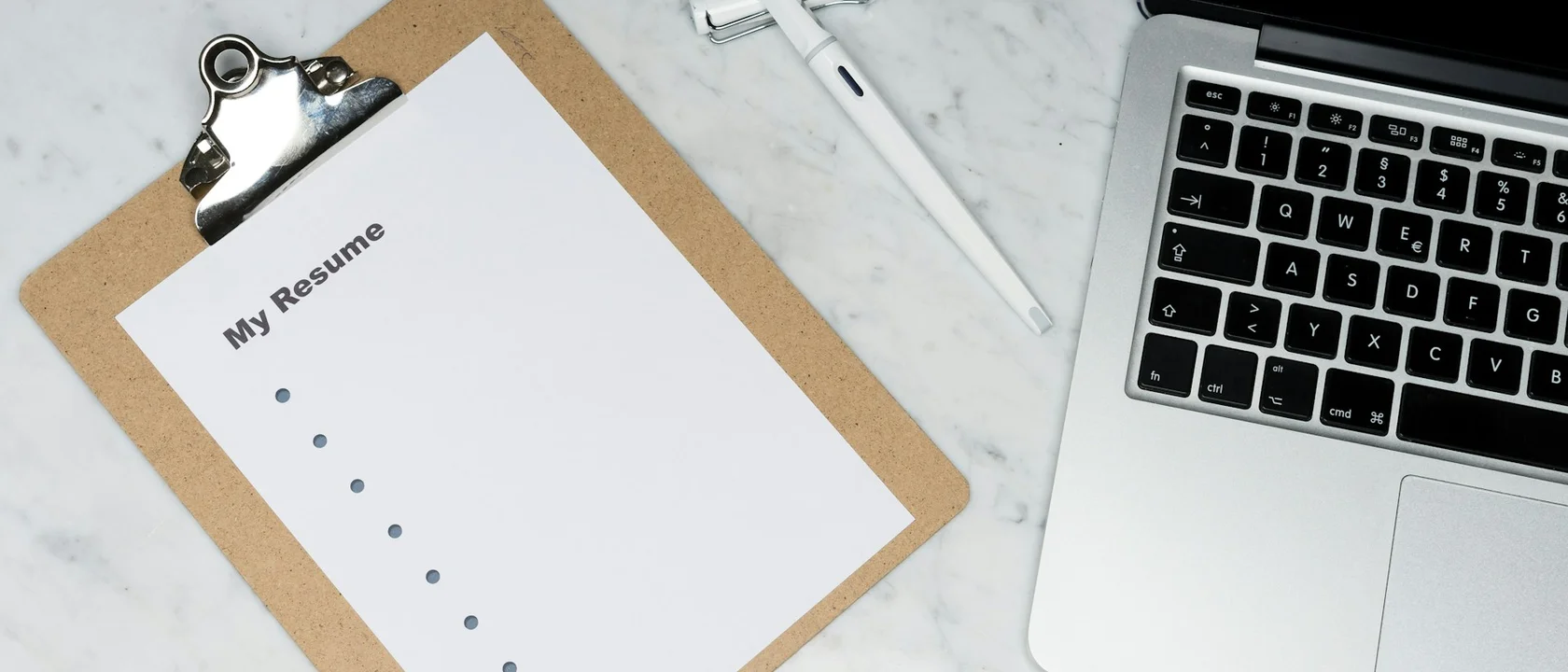 Printed form on a clipboard beside a laptop