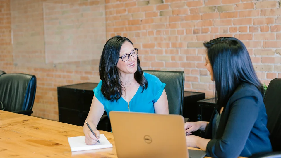 Hiring conversation around a table with laptops and printed role notes
