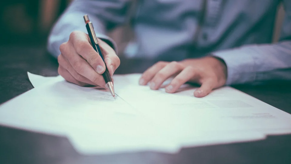 Person writing on a printed form