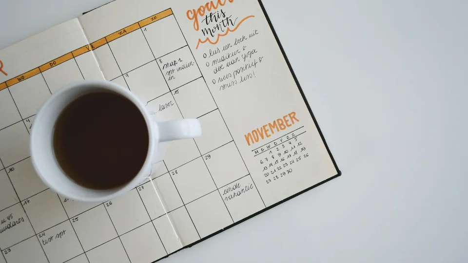 Open calendar planner with a coffee cup