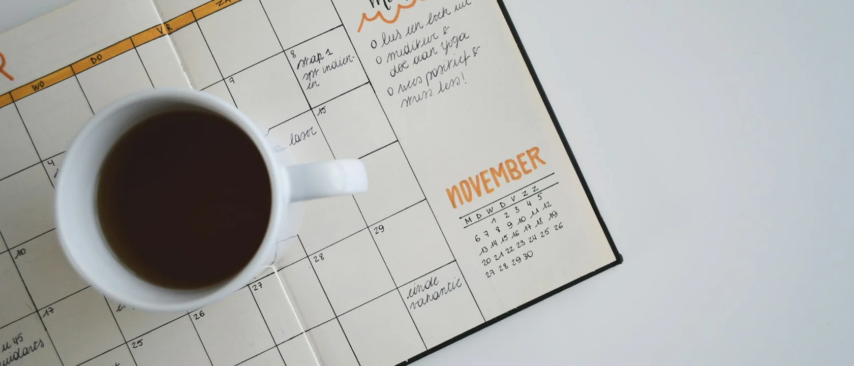 Open calendar planner with a coffee cup